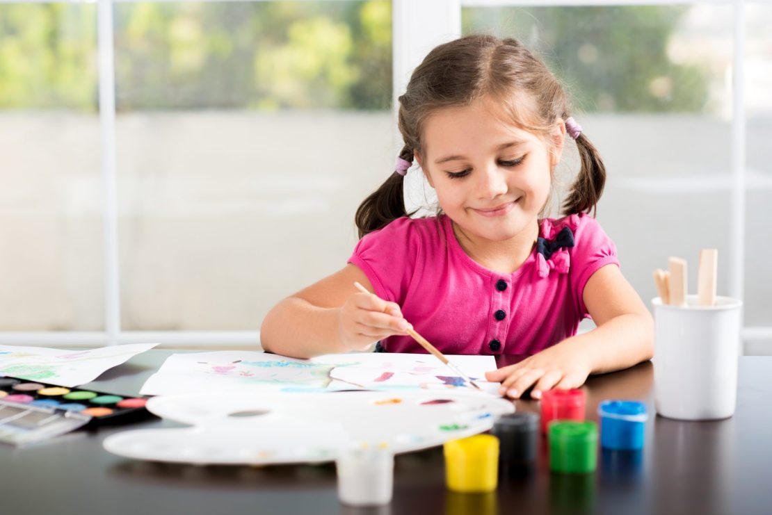 Young girl painting a fall-themed picture, engaging in a hands-on activity that supports creativity and academic skill development.