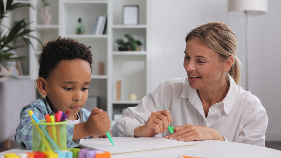 A dyslexia tutor working one-on-one with a child using magnetic letters and colored highlighters, demonstrating multi-sensory reading and writing instruction.