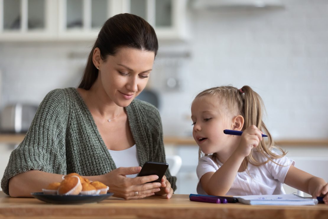 A parent sitting beside a child using a timer and planner during homework time, illustrating structured homework support strategies for a student with ADHD.