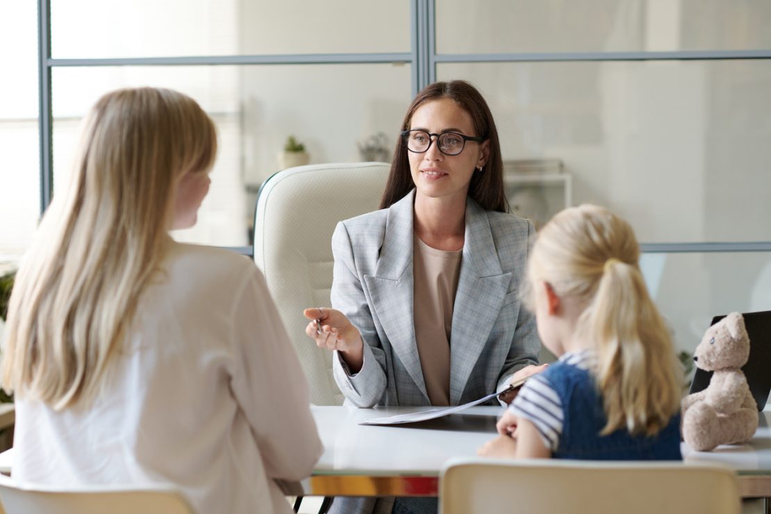A parent meeting with a tutor at a table reviewing notes and assessment papers, representing the process of choosing the right tutor for a child in NYC.