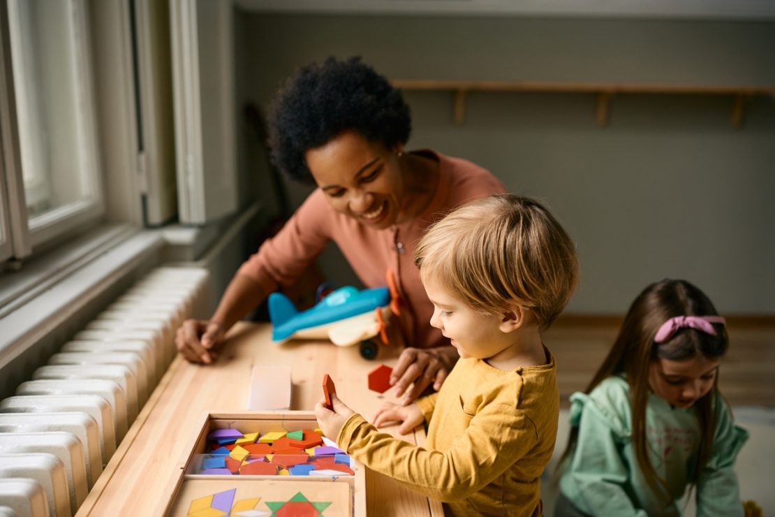 A young child working with a tutor using hands-on learning materials like letters and counting tools, illustrating early academic support for kindergarten students.
