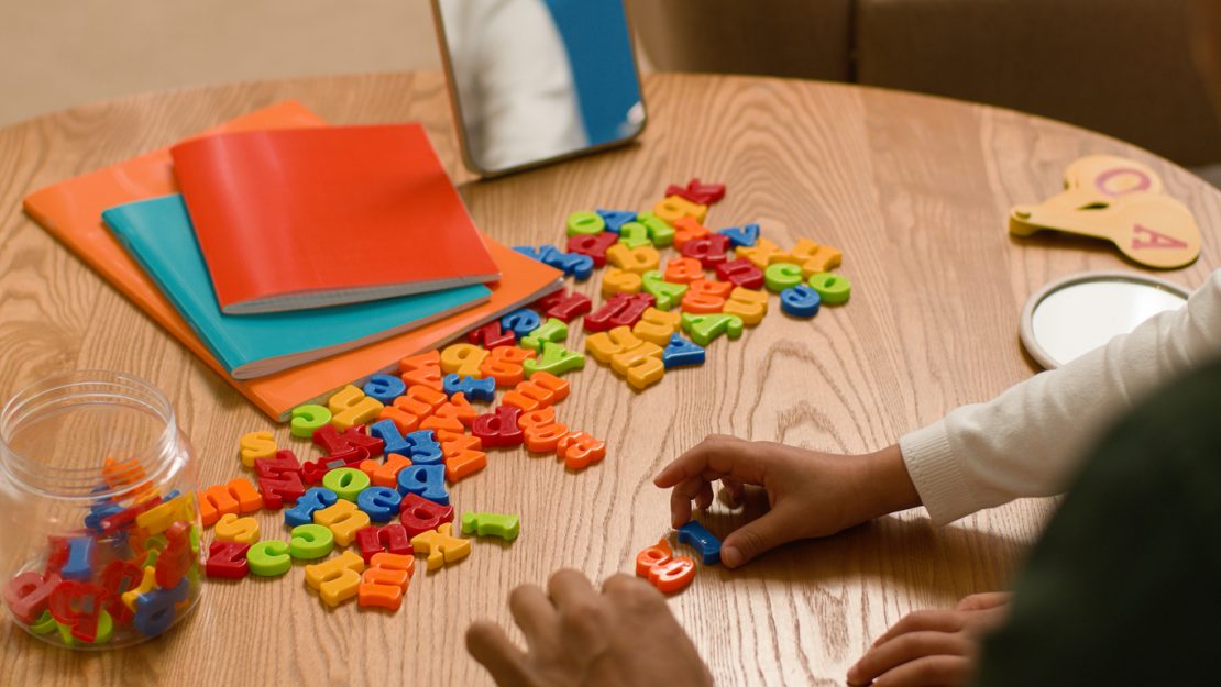 A tutor working with a child using multi-sensory reading tools like magnetic letters and sand tracing, illustrating Orton Gillingham tutoring in New Jersey.
