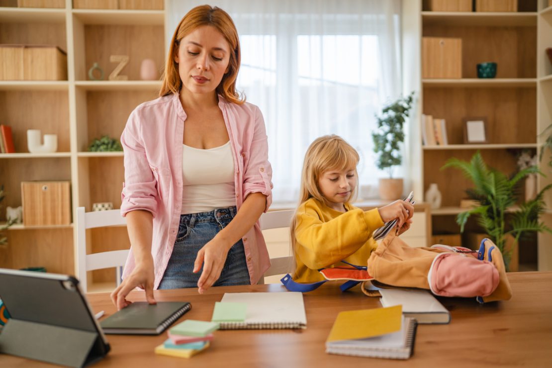 A parent and child organizing school materials and planning homework at a table, illustrating resetting academic habits during the spring season.