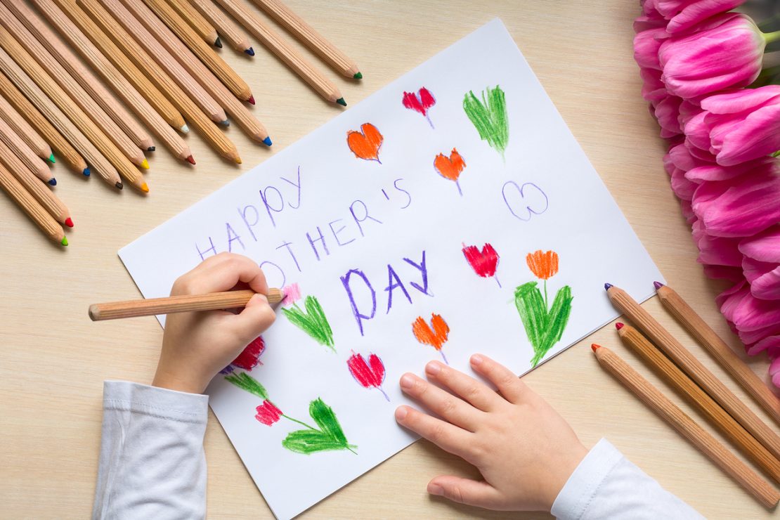 A child creating a handmade Mother’s Day card with writing prompts and decorations, illustrating a fun, structured activity for kids with ADHD.