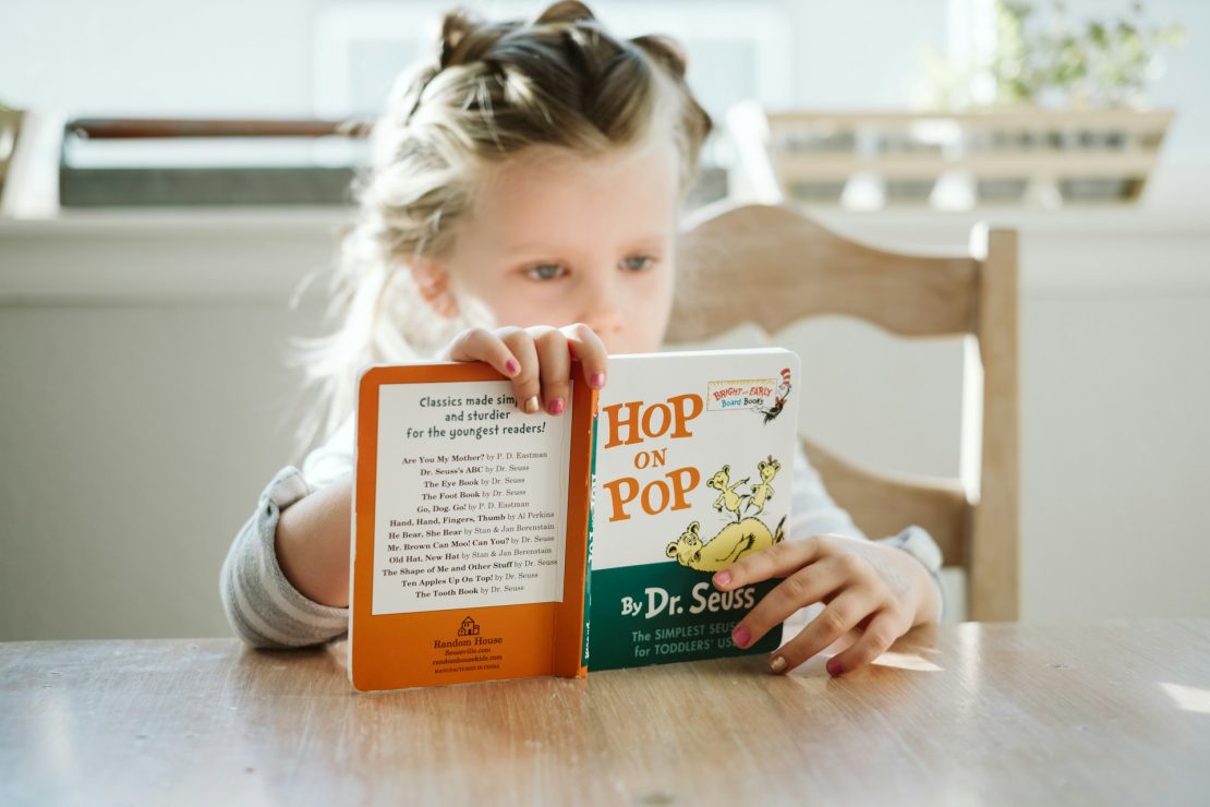 A child reading independently in a cozy reading corner with books nearby, demonstrating independent reading habits and literacy development.