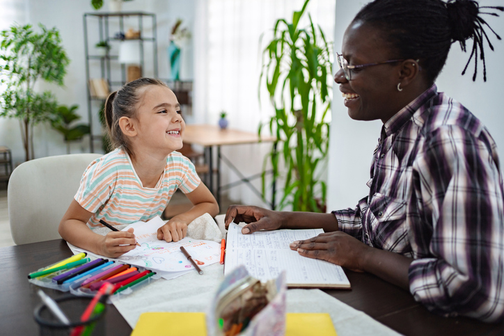 A child with dyslexia preparing for the new school year with books, a planner, and organized school supplies while receiving supportive reading guidance.