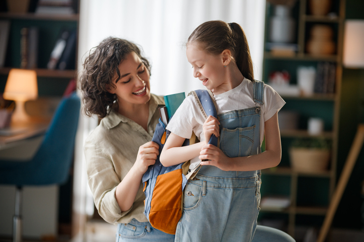 Parent helping a child with special needs prepare for the new school year using a visual schedule, organized school supplies, and a predictable routine.